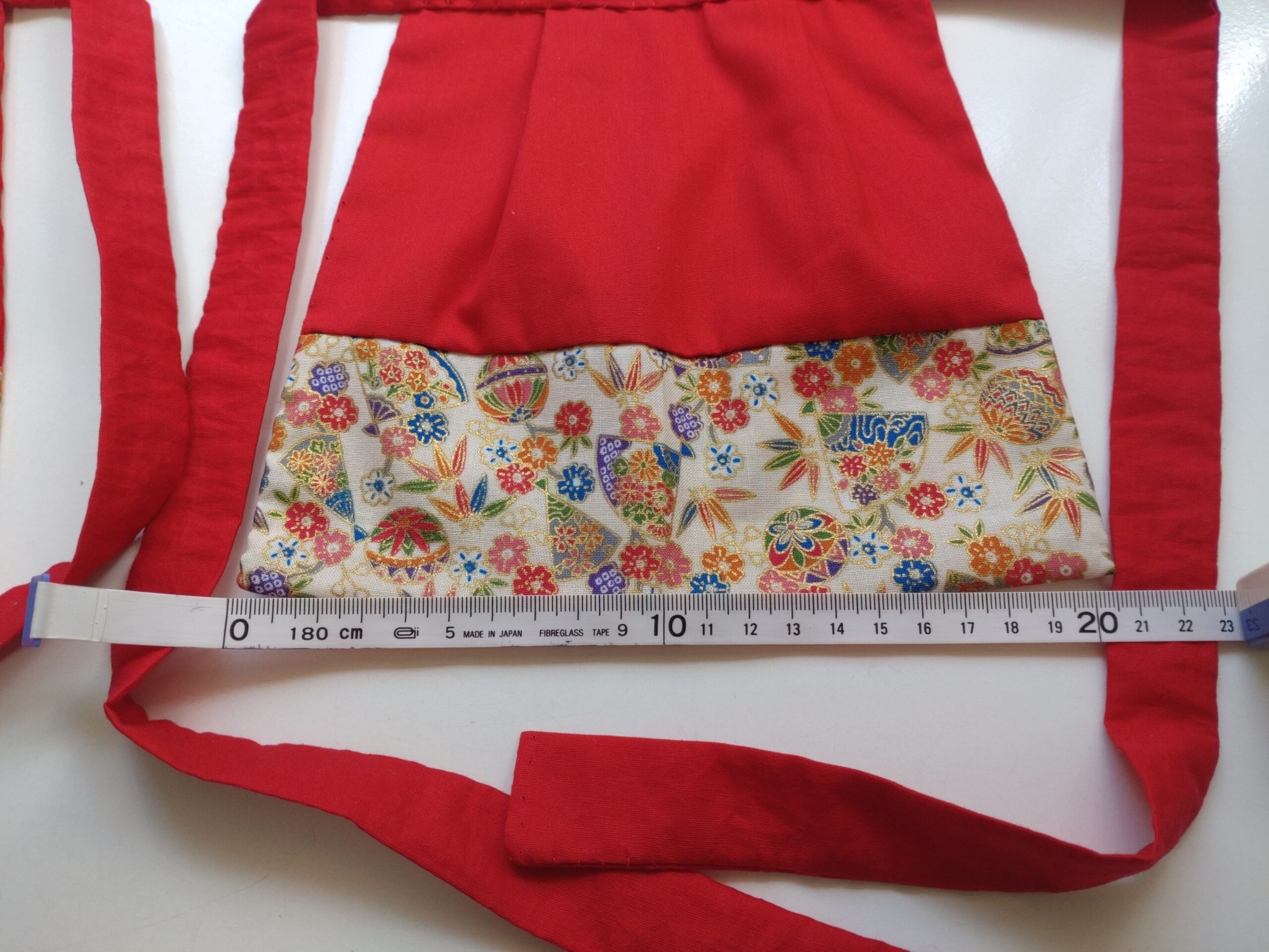 手作りしたお稲荷さんの前掛け。横を測っているところ
